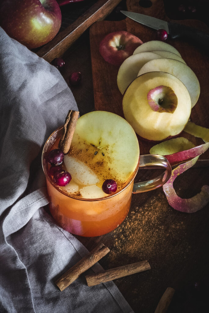 Apple Cider garnished with cinnamon, apple slices and cranberries.