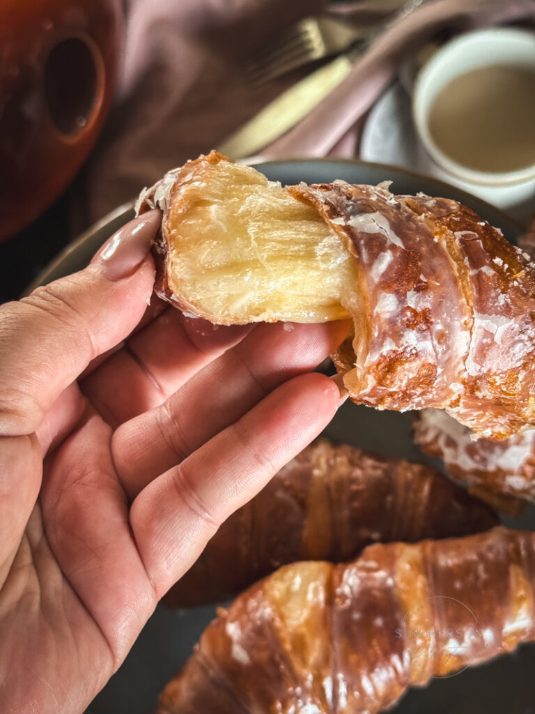 pulling apart glazed fried croissant