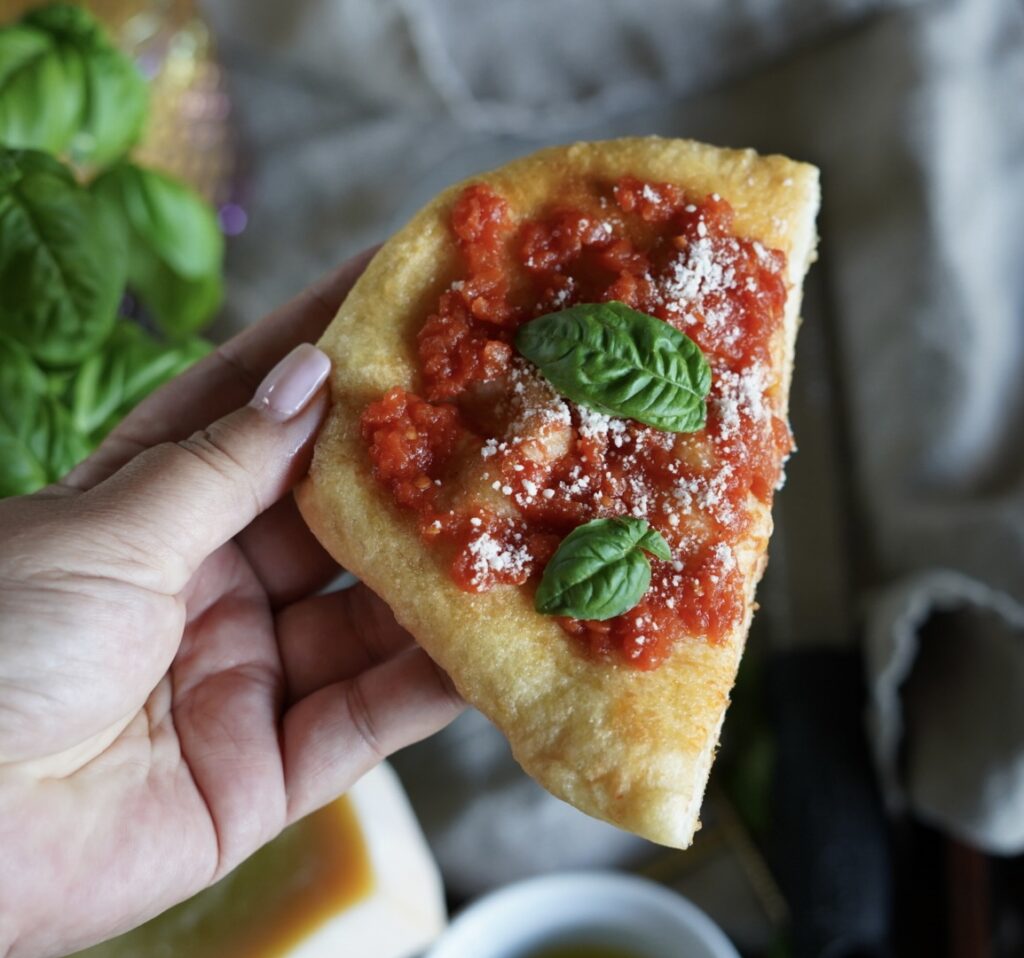 Hand holding Slice of fried pizza