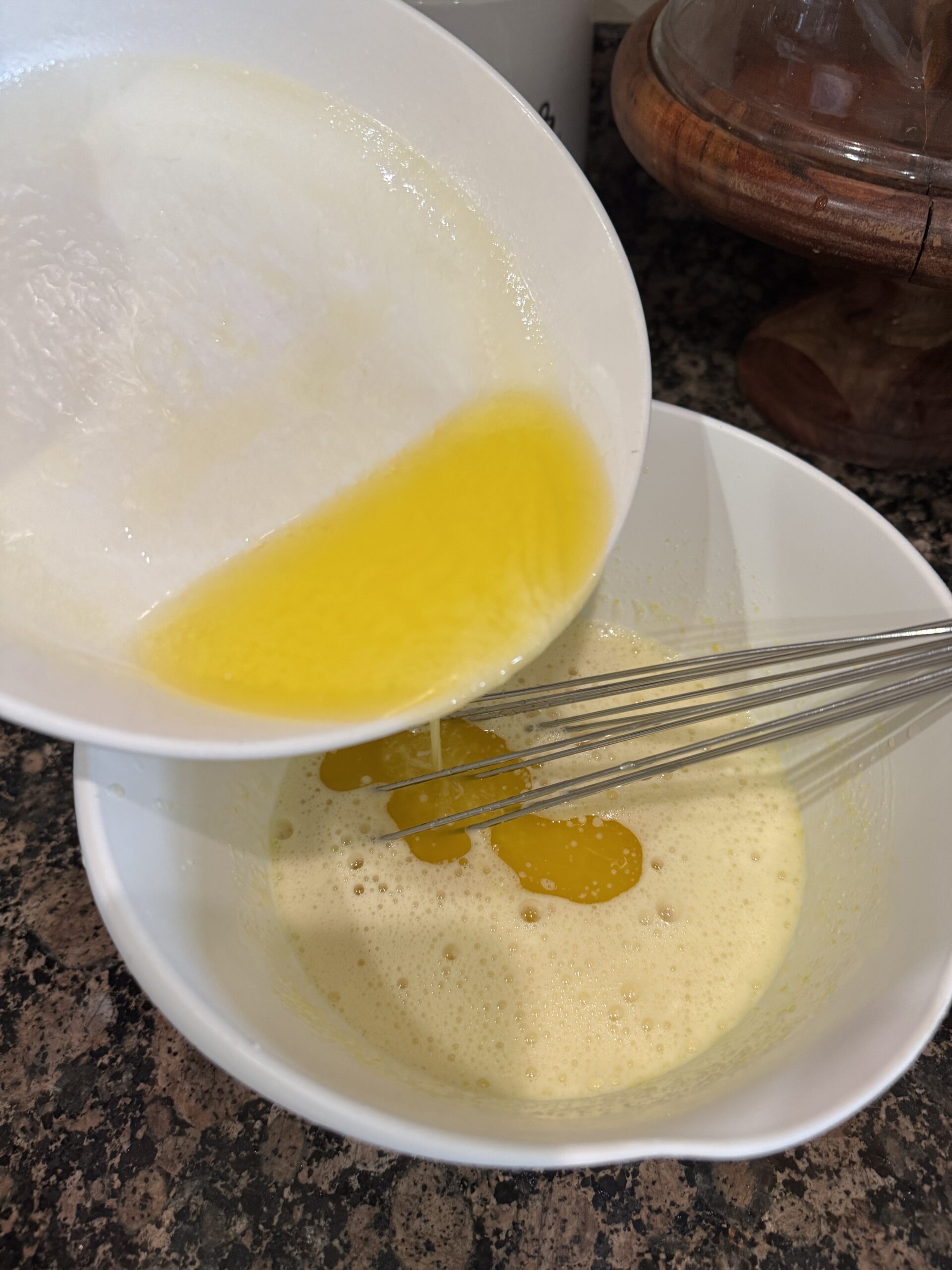 Adding melted butter to lemon juice, eggs and sugar in a bowl