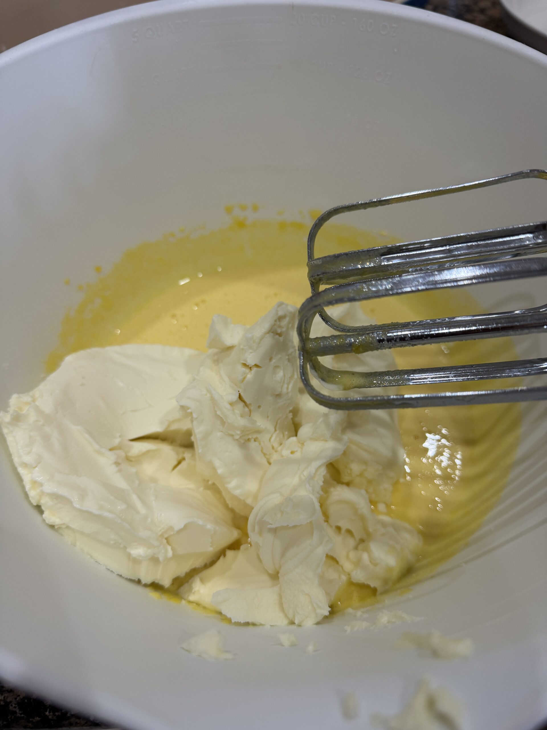 Adding mascarpone cheese to egg yolks and sugar in a bowl