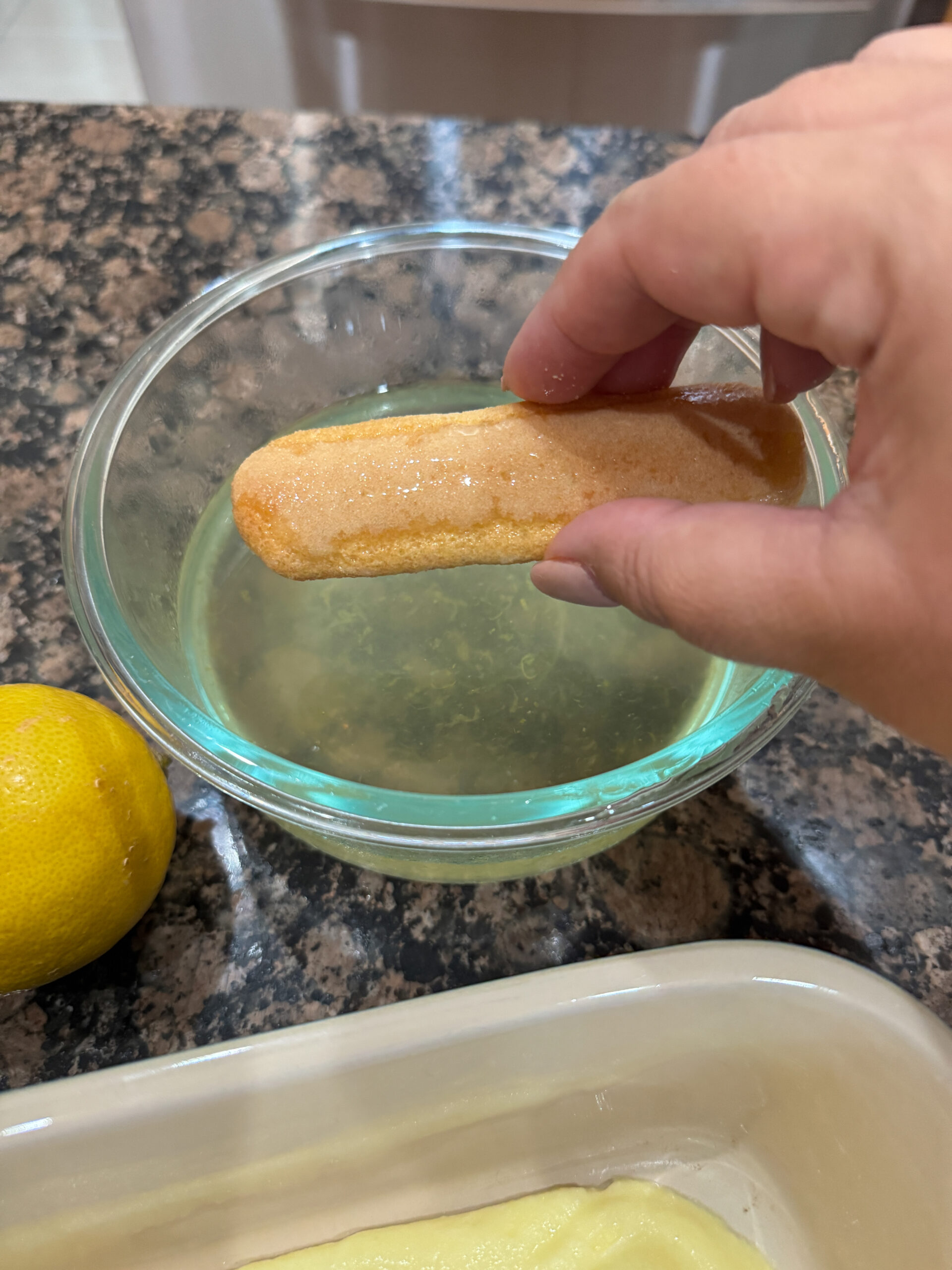 dipping ladyfingers into lemon simple syrup