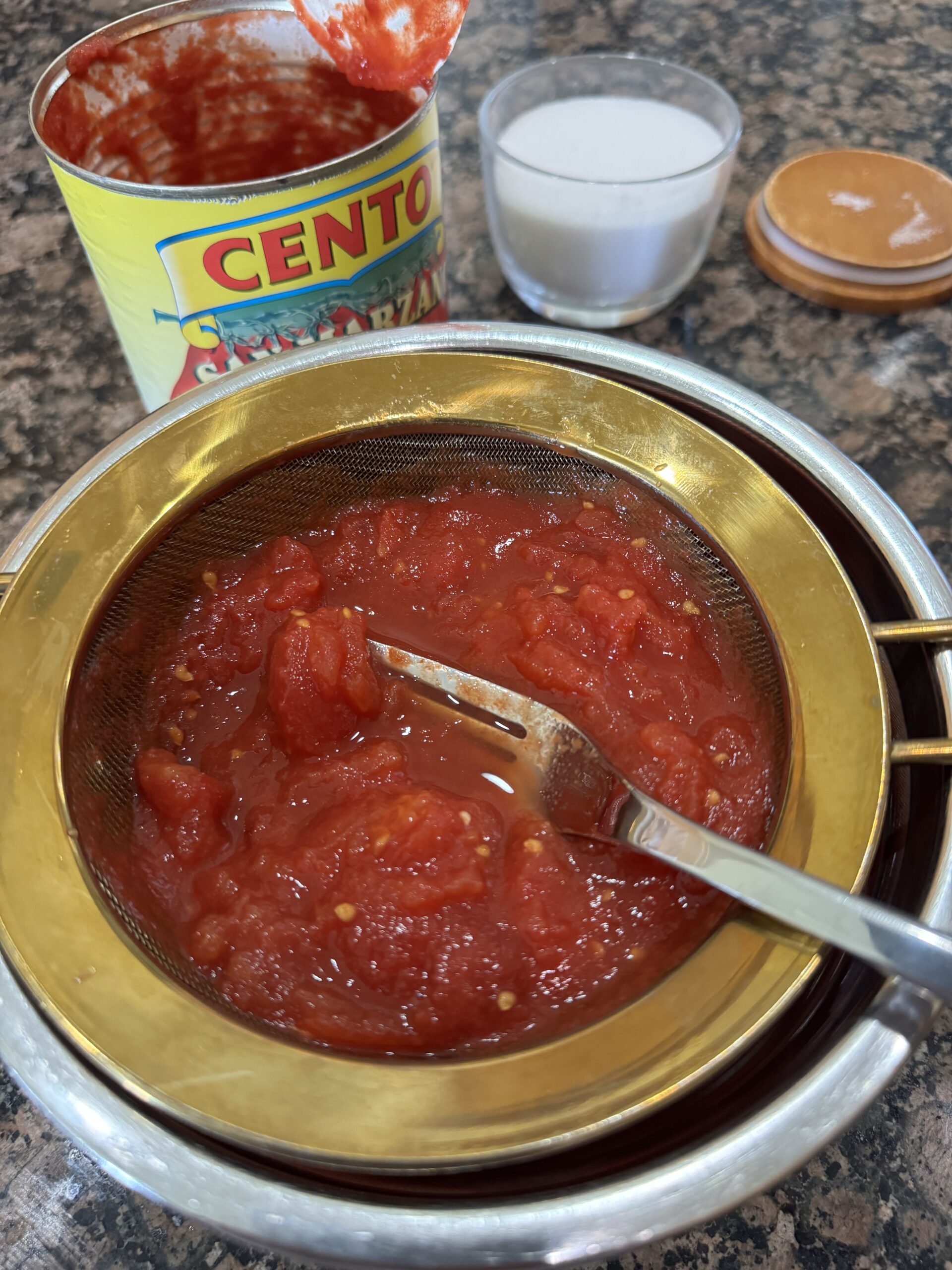 crushing canned tomatoes in strainer