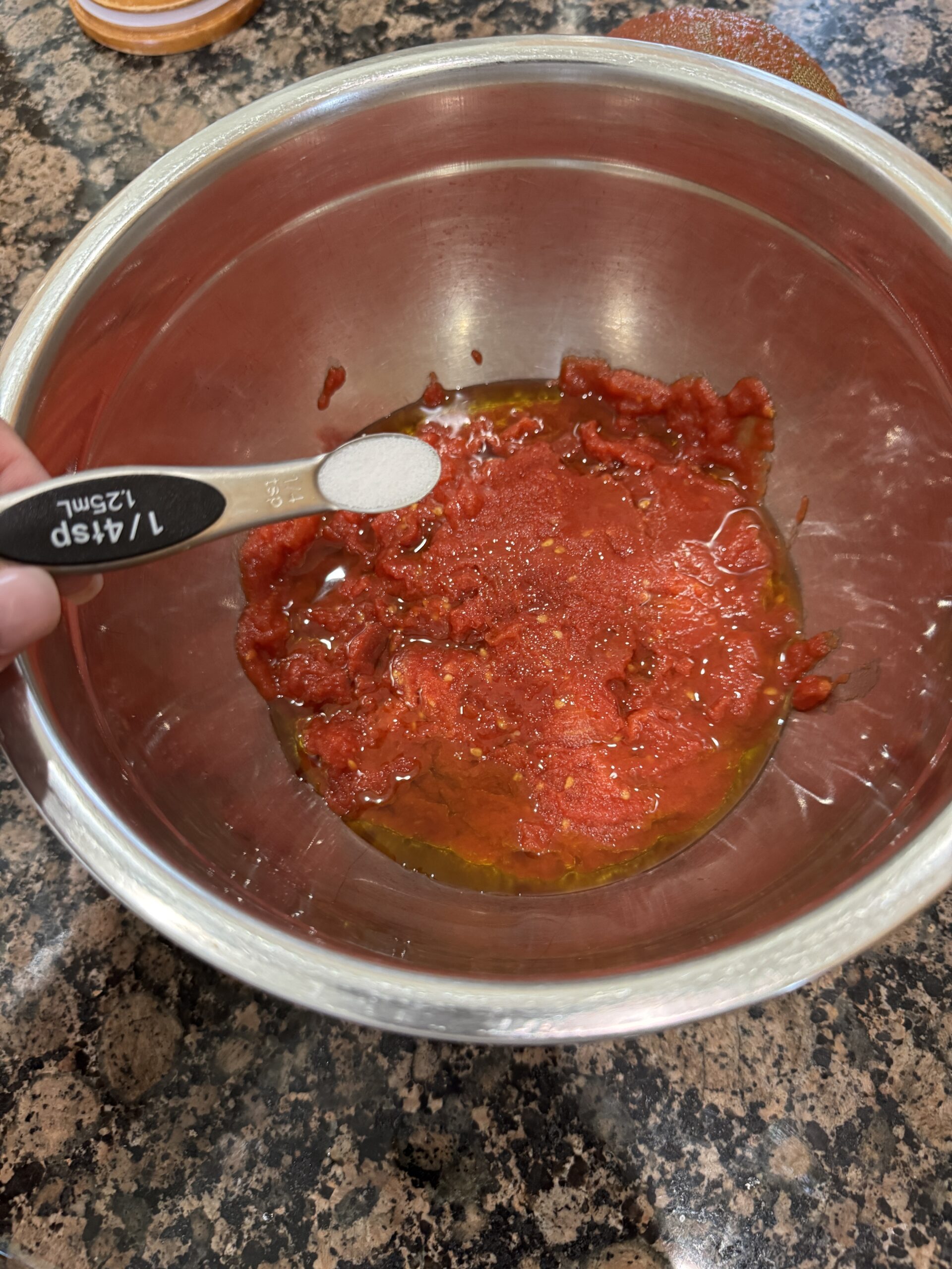 Adding salt to crushed canned tomatoes in bowl