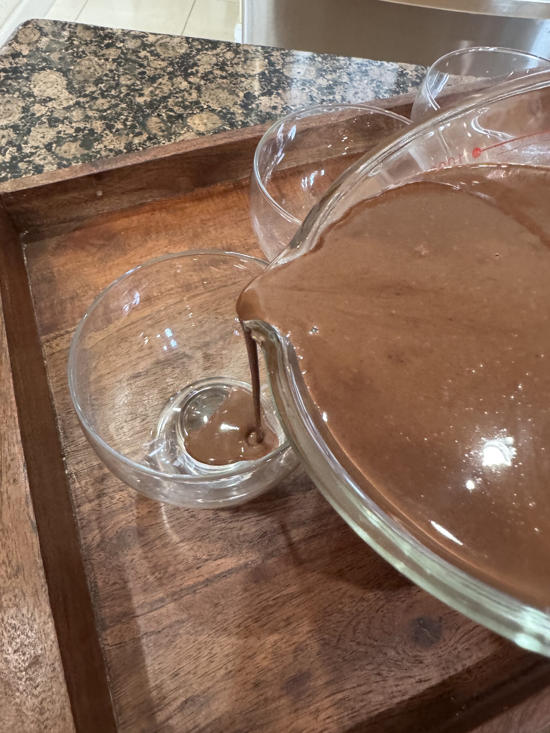 Pouring chocolate panna cotta mixture into dessert glasses